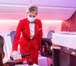 a stewardess in a virgin upper class cabin pouring wine for a guest