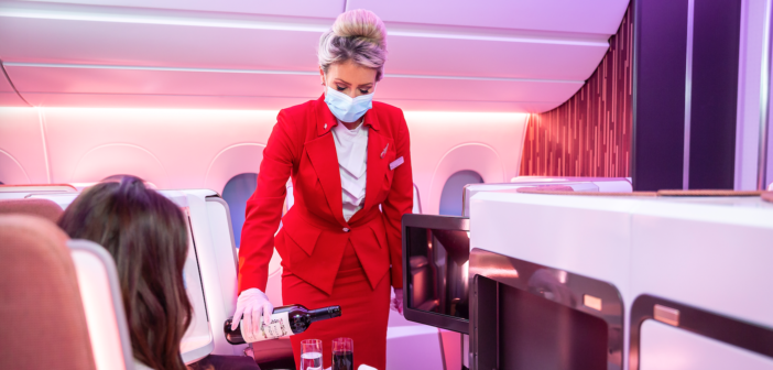 a stewardess in a virgin upper class cabin pouring wine for a guest
