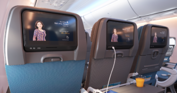 a row of economy class seats with entertainment screens