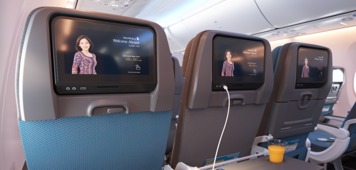 a row of economy class seats with entertainment screens