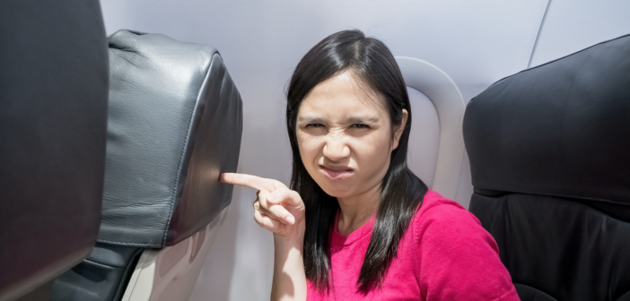 a female airline passenger unhappy with how close she is to the seat in front