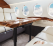 the cabin interiors of a business jet, with leather seating and a wood dining table