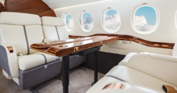 the cabin interiors of a business jet, with leather seating and a wood dining table
