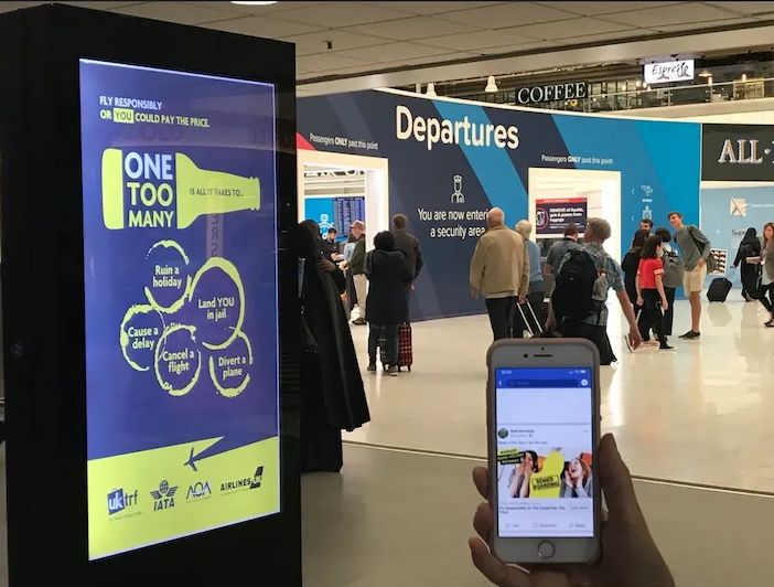 One Too Many campaign signage shown in an airport departure lounge, and on a passenger's mobile device